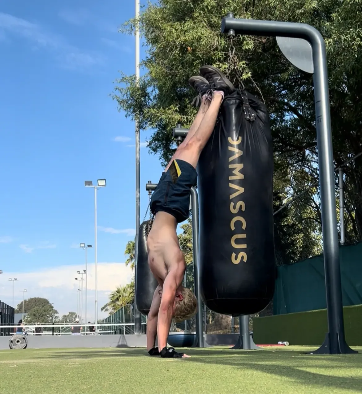 Alé in handstand position against a punching bag