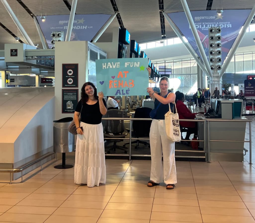 Alé's two friends holding a board with the words 'Have fun at rehab Alé'